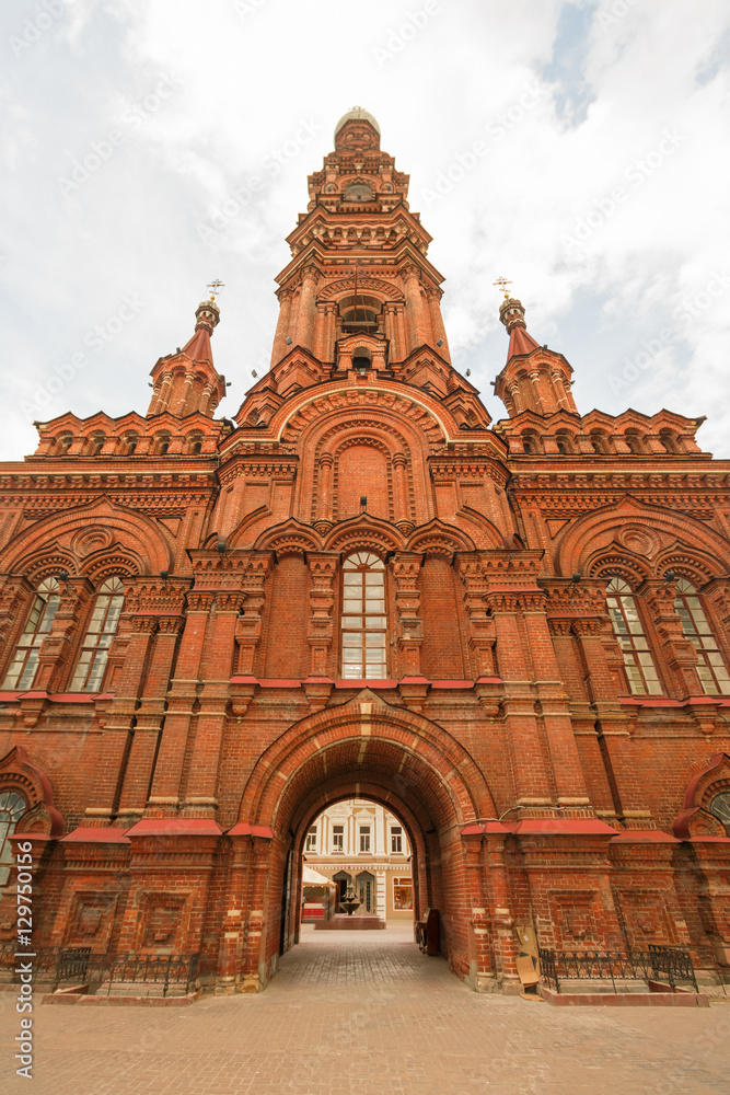 Beautiful orthodox church of red bricks, with a dome and crosses, against the blue sky