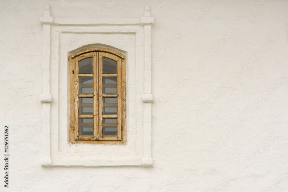 Window with wooden frame on a background of white stone wall