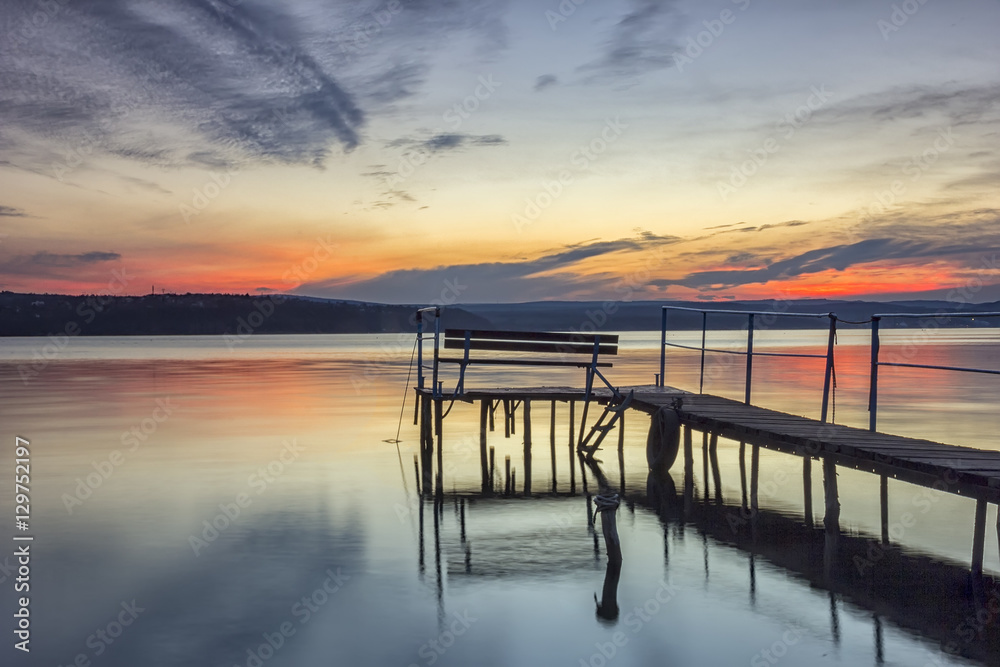 Fototapeta premium Beautiful long exposure sunset view with bench on wooden bridge