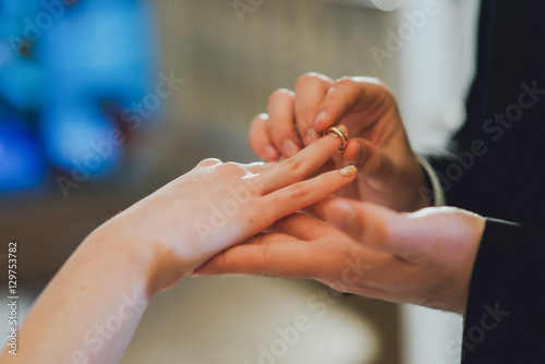 groom's hand putting a wedding ring on the bride' finger