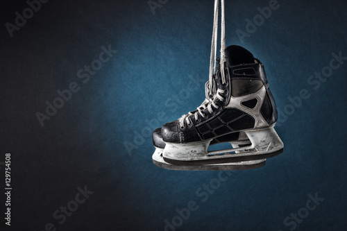 Fototapeta Men's hockey skates hanging on a dark background.