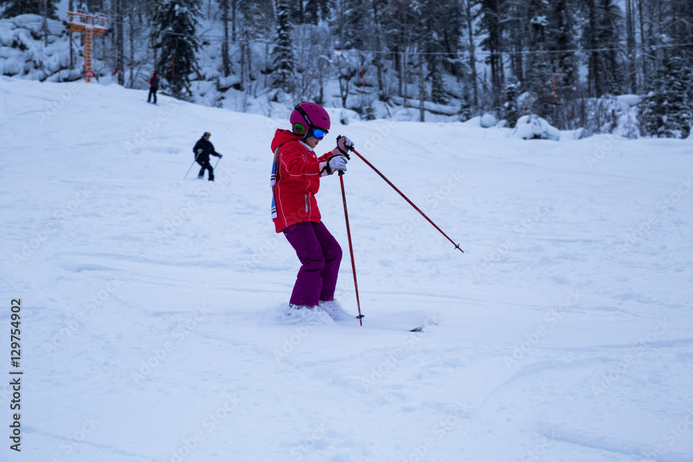 Happy child girl enjoying vacation in winter resort. Little  skiing in mountains. Active sportive toddler wearing helmet learning to ski.  sport for family. Skier racing in snow.