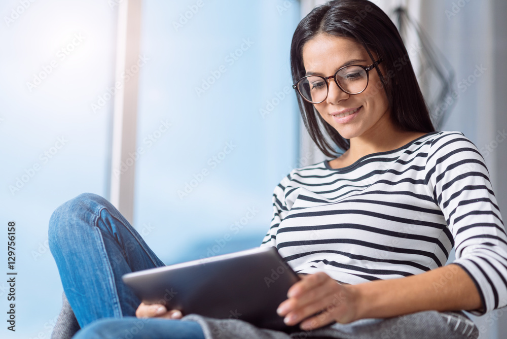 Involved pleasant woman using the tablet at home Involved pleasant woman using the tablet at home