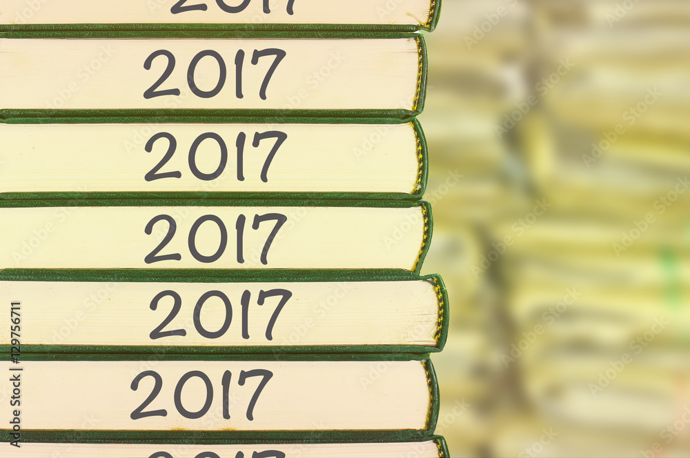 Obraz premium Stack of books and blur background with number year 2017