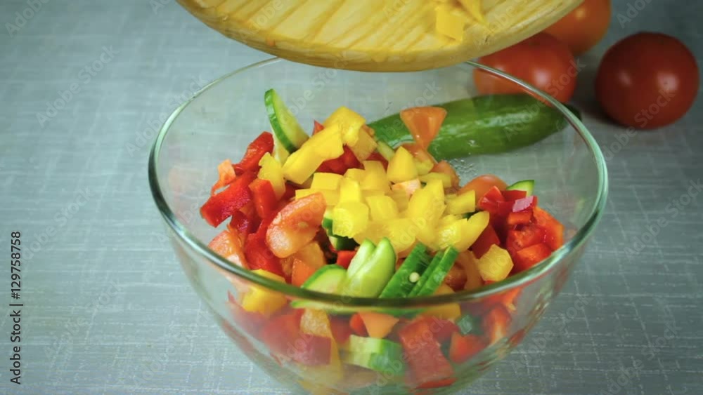 The girl cook pours in a bowl salad ingredients. Salad with cucumbers, tomatoes, arugula, peppers. The girl cook pours in a bowl salad ingredients. Salad with cucumbers, tomatoes, arugula, peppers.