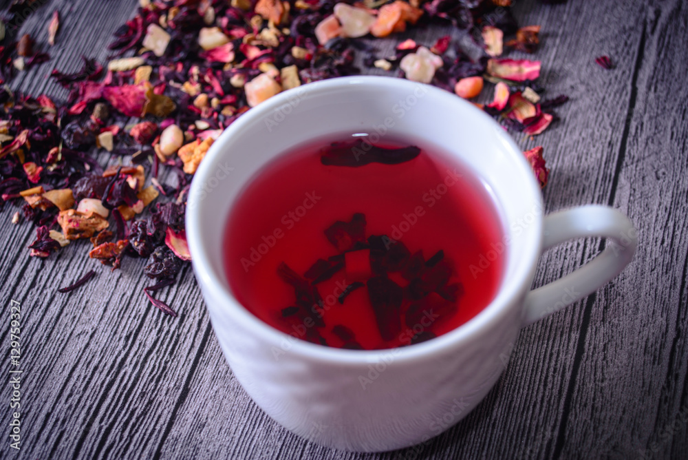 Cup of tea mix of leaves, fruits and dried fruits on rustic back