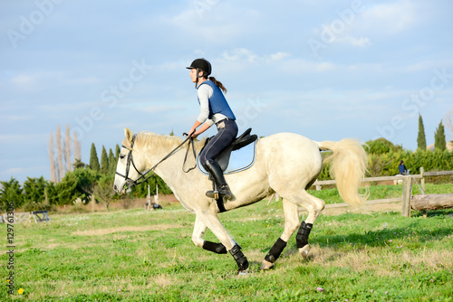 beautiful young woman riding horse and training for jump hurdle equitation competition outdoor