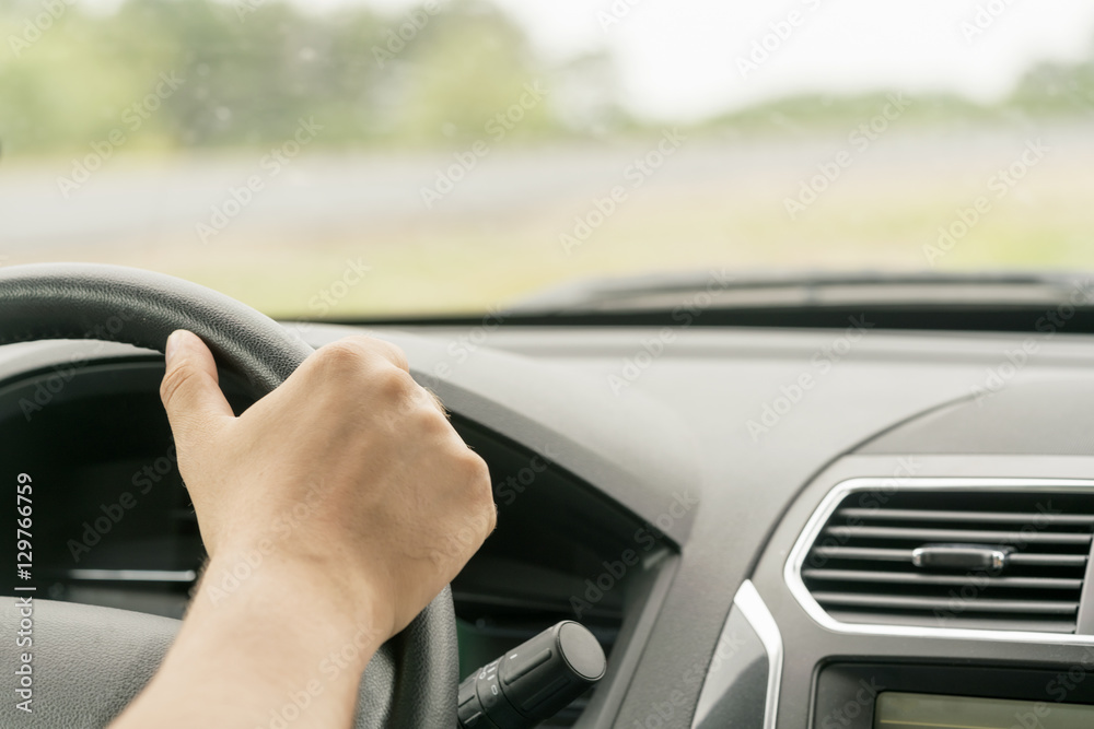 Human hand holding the steering wheel in the car