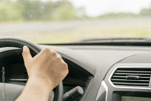 Human hand holding the steering wheel in the car