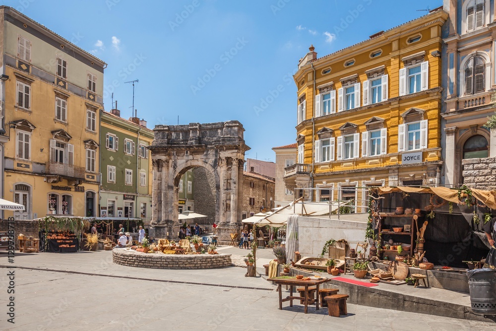Fototapeta premium Pula, Croatia-10 June, 2016. Ancient Roman triumphal arch or Golden Gate and square decorated for the Days of Antiquity - Pula Svperiorvm on 10 June, 2016 in Pula, Croatia. 