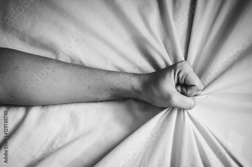Foto young woman in bed clutching tightly her Bed linen