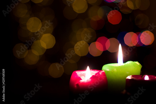 Three candles on a Christmas tree background.