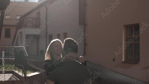 A couple in love swirling around, smiling, kissing at the sunset in city, slow mo