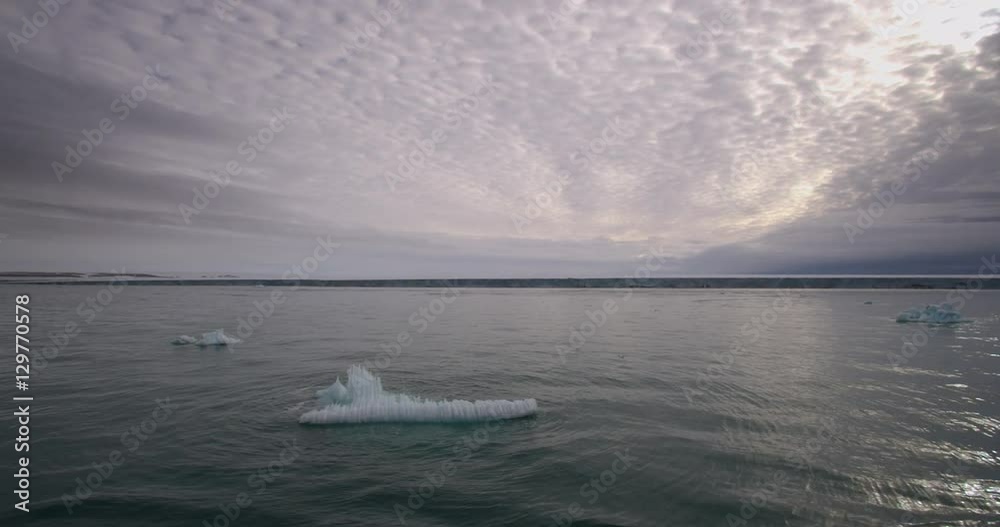 Passing through small icebergs on calm arctic ocean at dusk Passing through small icebergs on calm arctic ocean at dusk