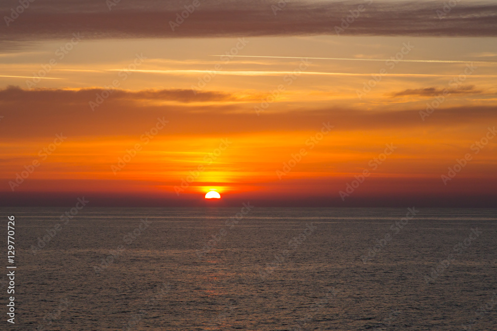Fototapeta premium Sunset at sea with sun, clouds and horizon