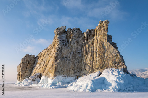 Rock surrounded by ice on blue sky background © Aniland