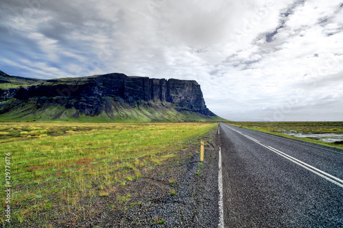 Strada lunga e dritta in islanda con roccia sullo sfondo