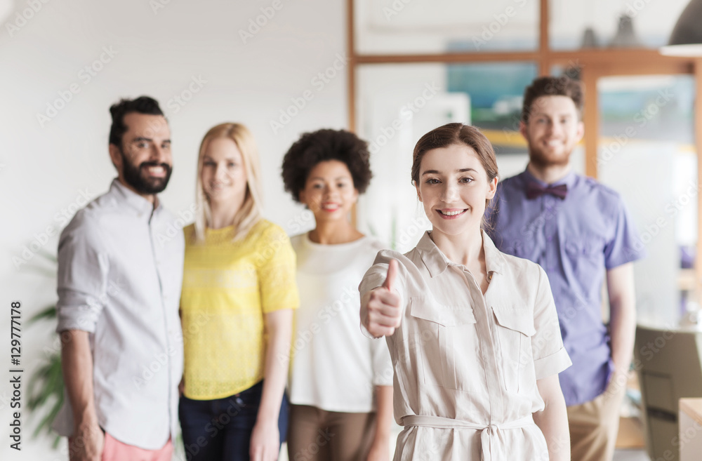 woman showing thumbs up over creative office team woman showing thumbs up over creative office team