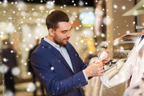 happy young man choosing clothes in clothing store