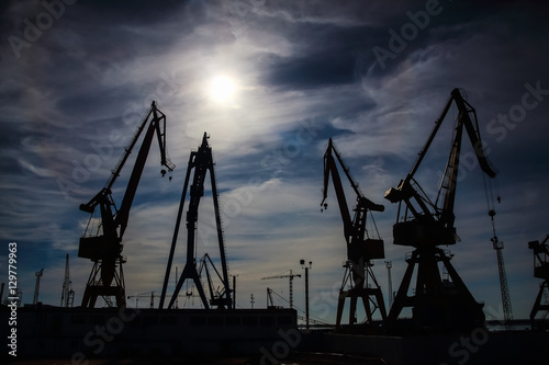 Beautiful landscape of cranes in shipyard against a backlight in coast of Huelva, Andalusia, Spain.