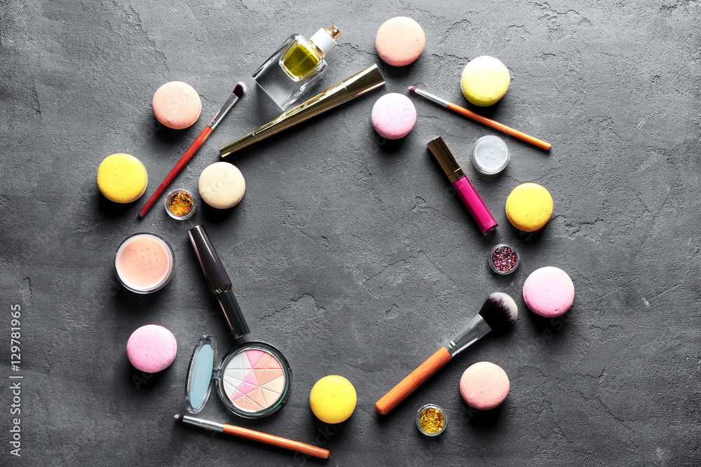 Makeup products and macaroons on grey background