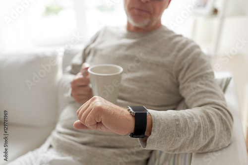close up of old man with mug looking at wristwatch