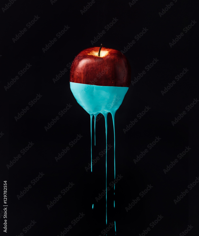 Fototapeta Czerwone jabłko z kapiącą niebieską farbą. Minimalna koncepcja żywności.