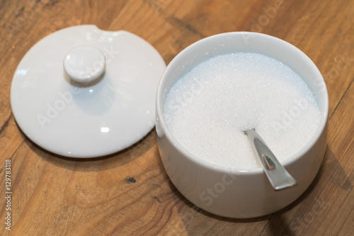 White sugar in glass bowl with teaspoon 