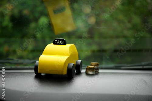 Yellow toy taxi with coins on car dashboard © Africa Studio