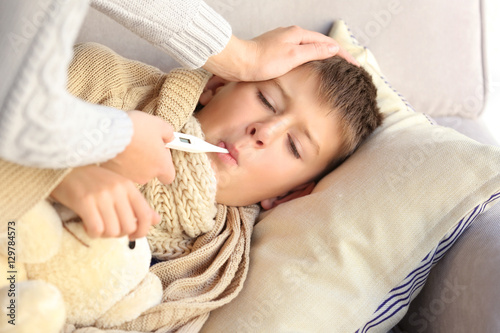 Small sick boy with thermom...