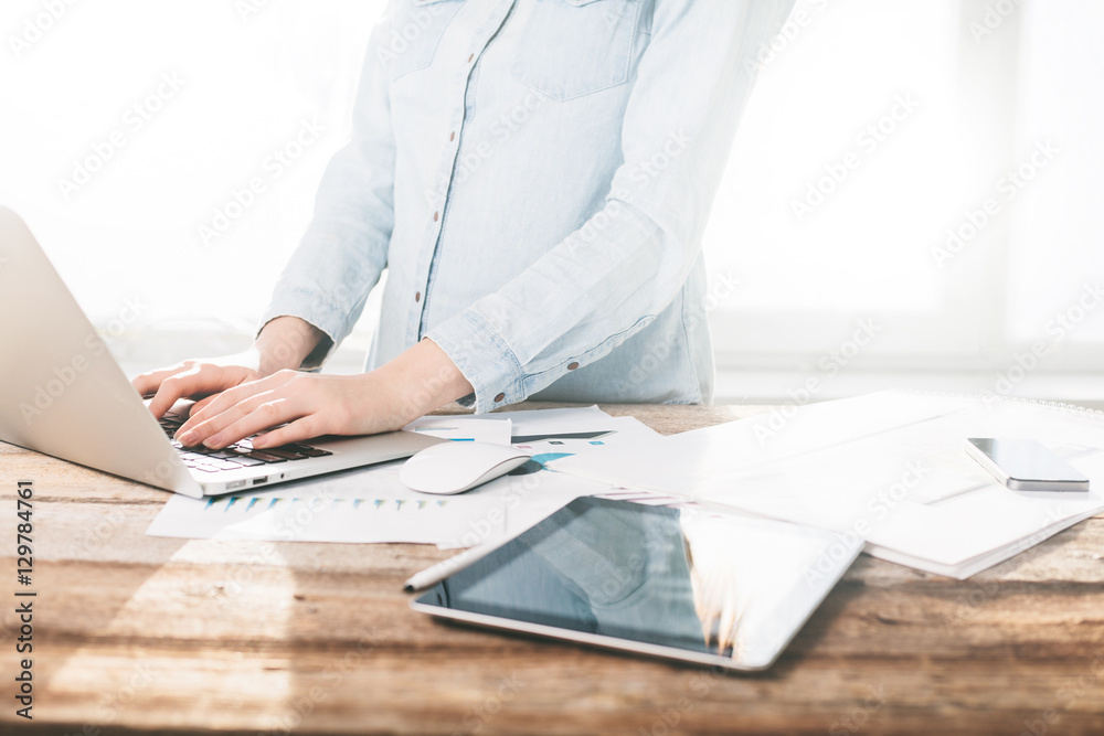 Woman working on a laptop and tablet pc indoor on a wooden stand Woman working on a laptop and tablet pc indoor on a wooden stand