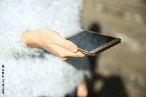 Woman holding modern cellphone, outdoor