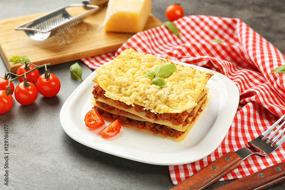 Plate with tasty lasagna on grey table Plate with tasty lasagna on grey table
