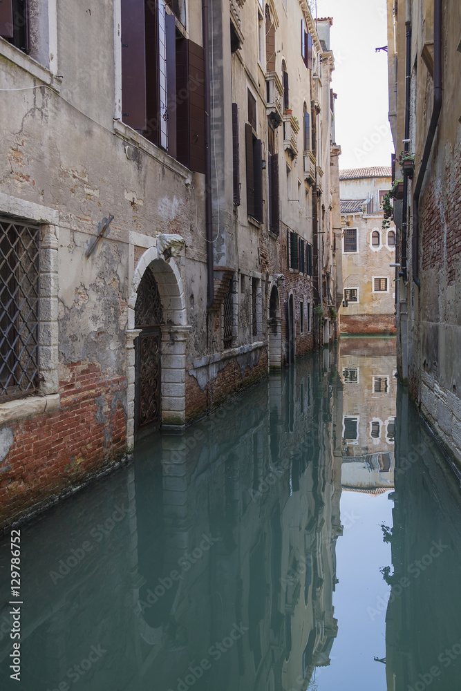 Vintage Venetian facades and gates reflects in calm canal water