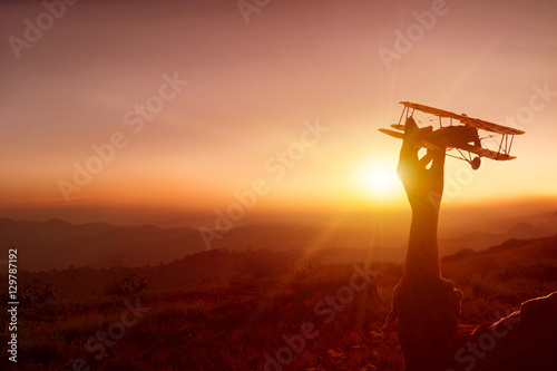 Silhouette Woman hand and toy airplane in the sunset.