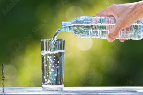 Man's hand holding plastic bottle water and pouring water into g