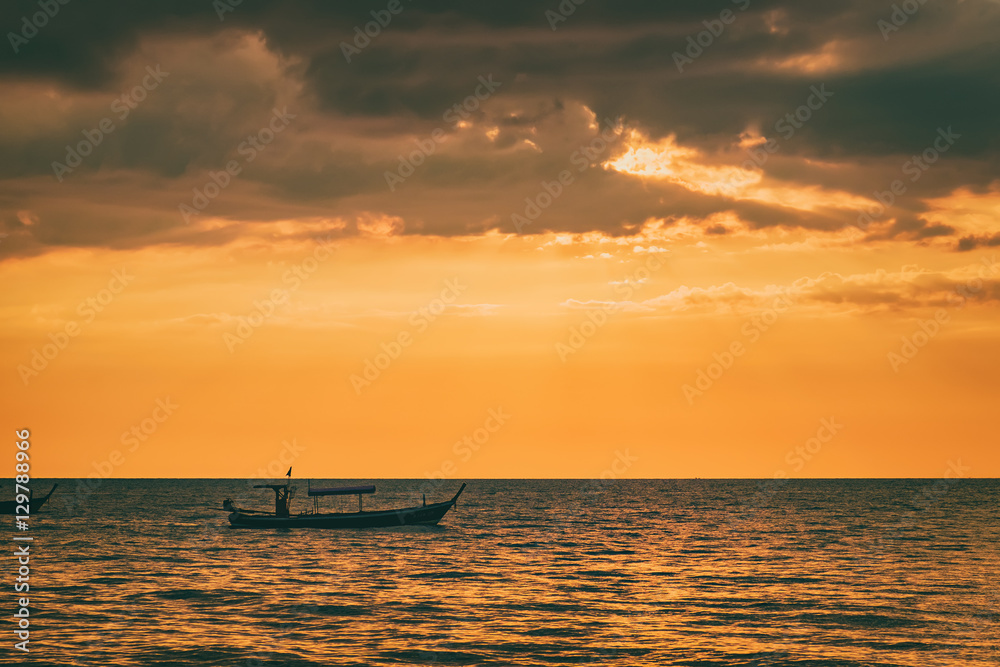 Sunset by The Andaman Sea. Fishing boats pull their nets. Silhouette boat in the sunlight.