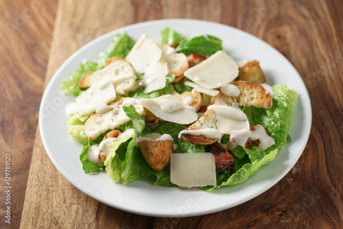 caesar salad with chicken on old wooden table, shallow focus
