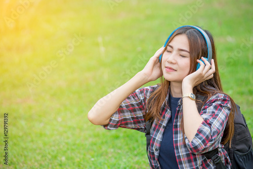 portrait of young  asian woman listening music on green grass