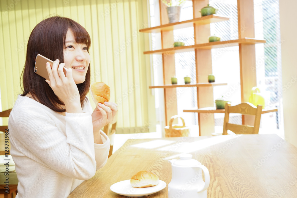 Young woman using a smartphone while eating breakfast Young woman using a smartphone while eating breakfast