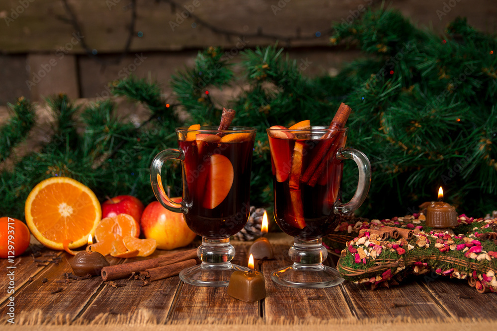 Christmas mulled wine with fruits and spices on wooden table. Xmas decorations in background. Two glasses. Winter warming drink  recipe ingredients around.