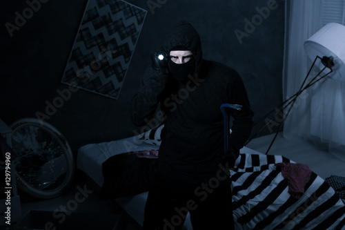 Robber holding flashlight and crowbar