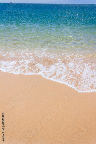 Strandsand im Sommer mit türkis-blauem Wasser.