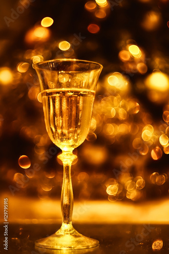 festive atmosphere in the evening with a glass of champagne and bokeh. Christmas, New Year's atmosphere. golden color, soft focus, monotony. 