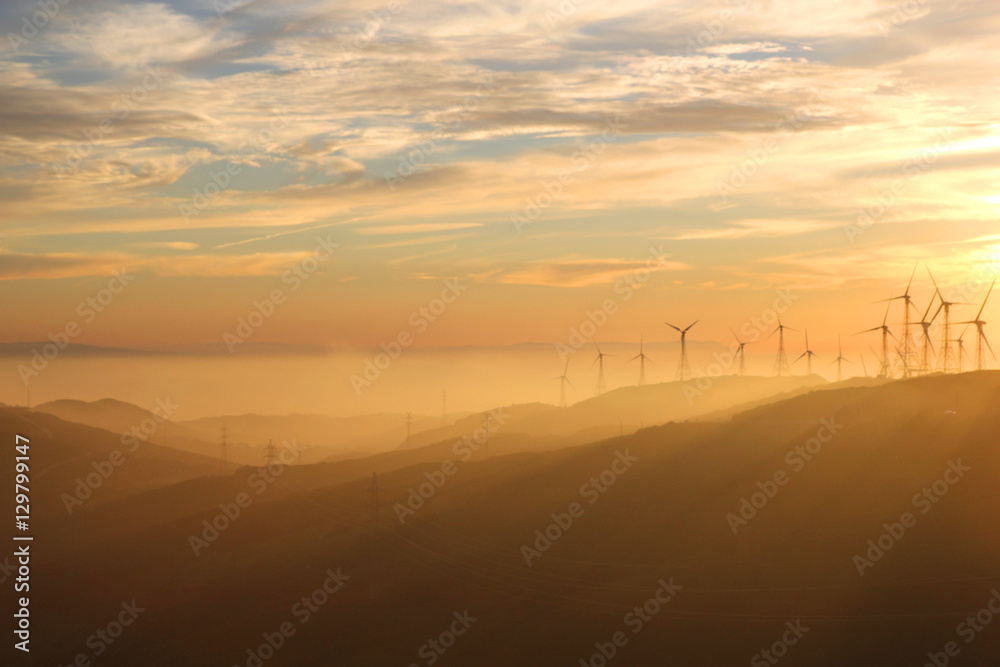 Obraz premium Wind turbines during sunset with Andalusian hills, Atlantic ocean and mountain of Africa on background.