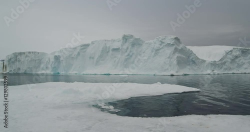 Scenic pan of iceberg in calm seas in arctic evening photo