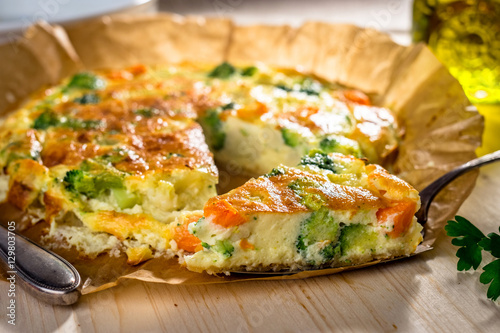 Homemade vegetable quiche on wooden background