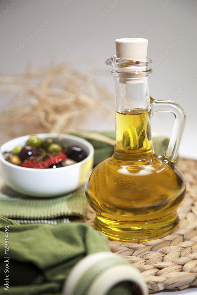 extra virgin olive oil in glass bottle with green olives and napkin 