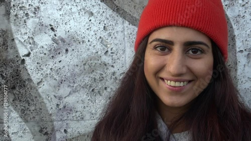 Beautiful young multiracial female wearing an orange wool hat and smile happy face portrait. Beautiful young multiracial female in city, smile happy face portrait.