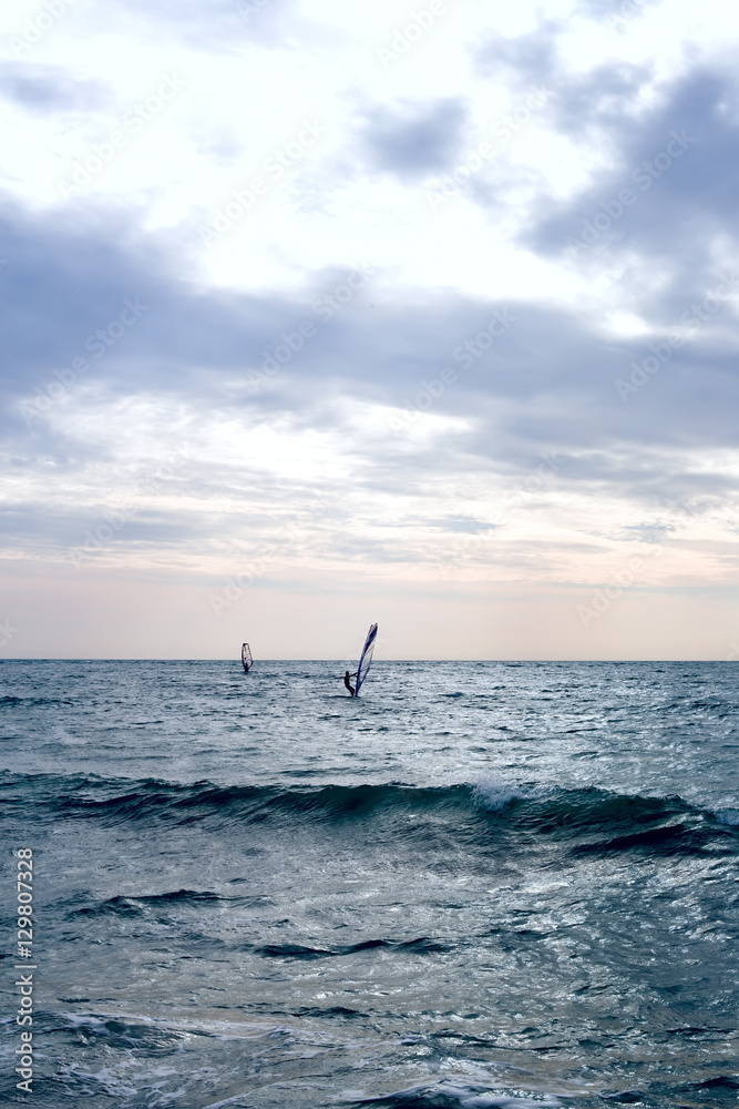 Group of windsurfers on boards in wavy sea